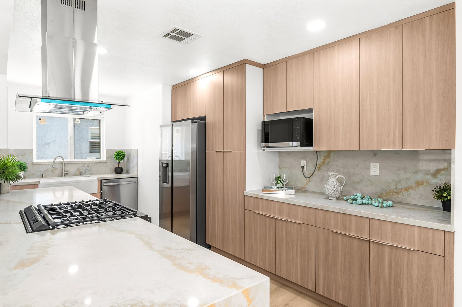 Floor to ceiling oak cabinetry with full-height quartz backsplash