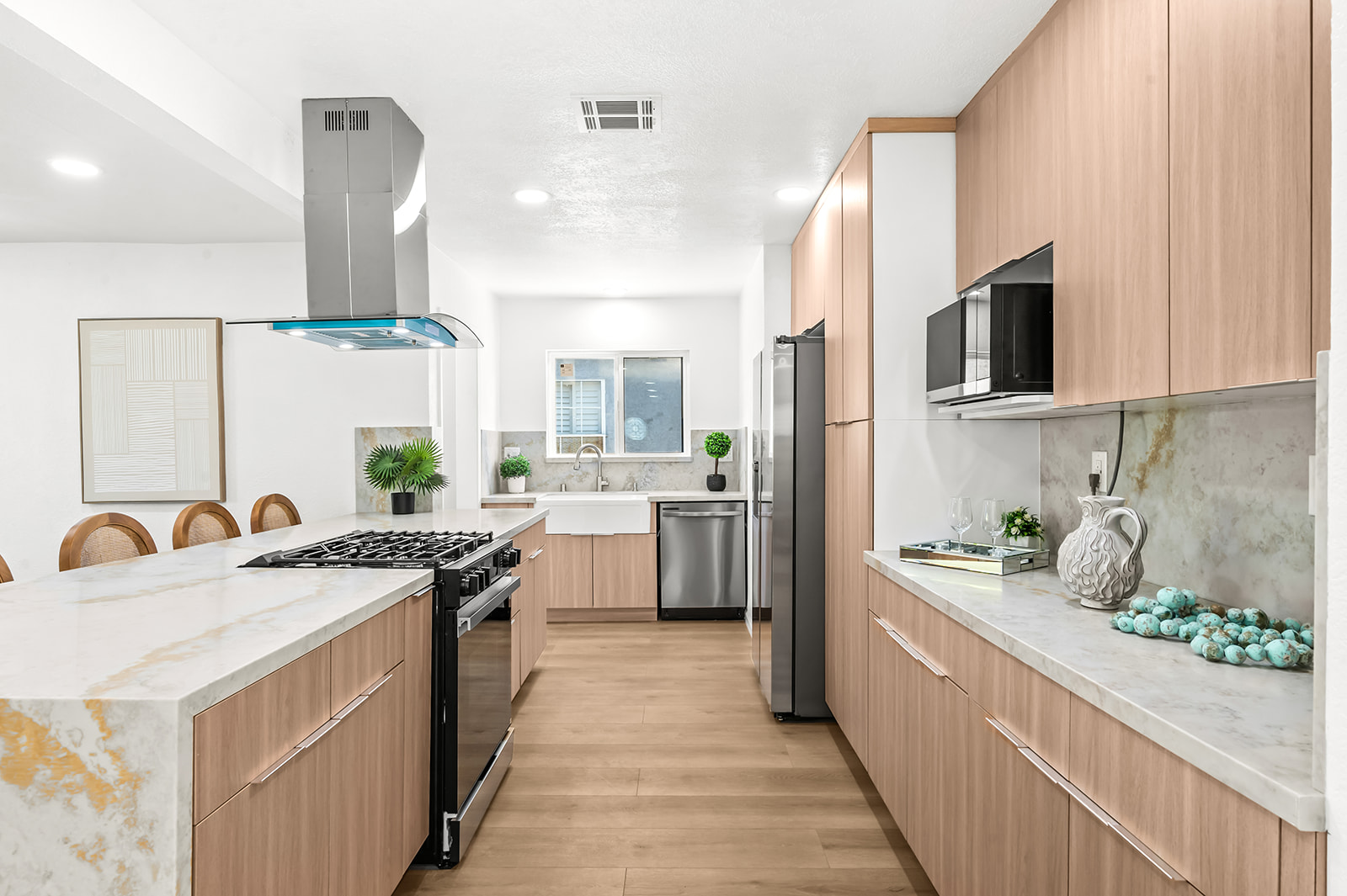 Galley view of the kitchen with waterfall island and curved-glass hood